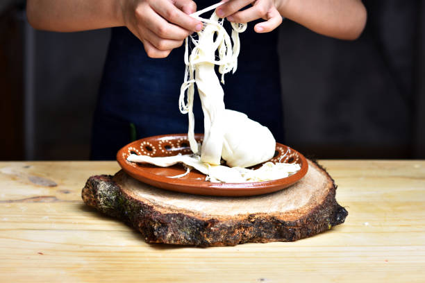 hands separating oaxaca cheese hands separating oaxaca cheese on a plate oaxaca city photos stock pictures, royalty-free photos & images