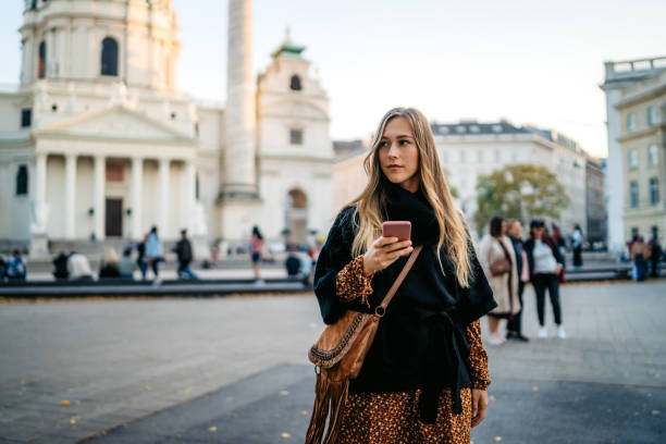 Woman text messaging in Vienna Woman sitting and holding mobile phone at square. heldenplatz stock pictures, royalty-free photos & images