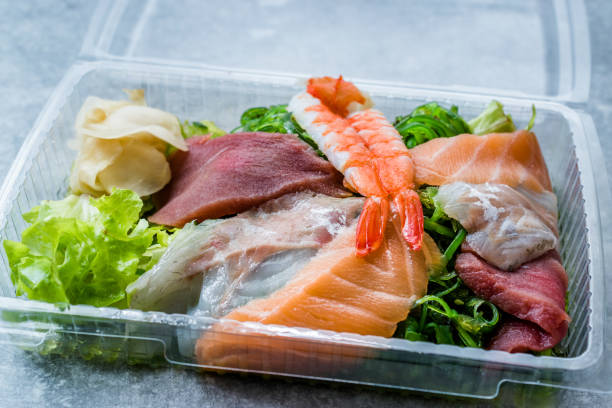 take away sashimi salat mit wakame, algen, lachs, seebarsch, garnelen, kani, makrele fisch, thunfisch in kunststoff-box-paket / behälter. - sashimi sushi salad sea stock-fotos und bilder