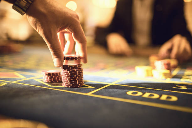 les joueurs de main font des jetons de paris pour jouer à la roulette dans un casino - roulette wheel photos photos et images de collection