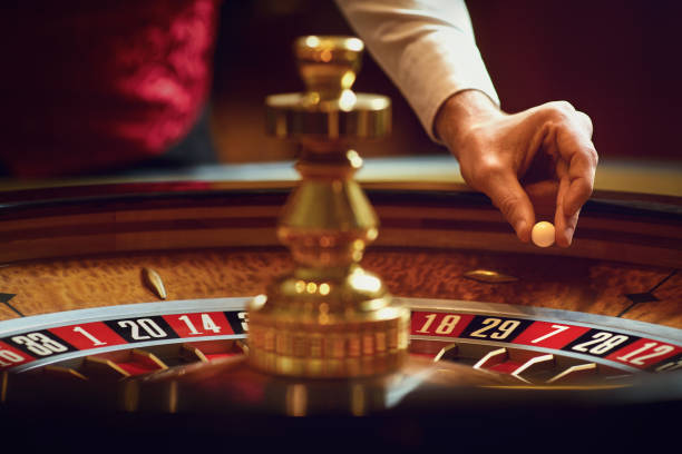 mano di un croupier con una palla su una ruota della roulette durante una partita in un casinò. - croupier foto e immagini stock