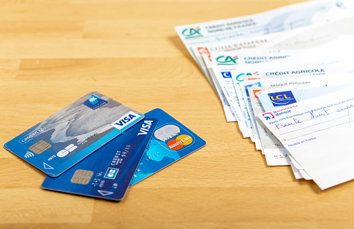 Paris, France - November 18, 2019 : Checks of different french banks and credit cards set on a wooden desk. France is the European country where checks are most used