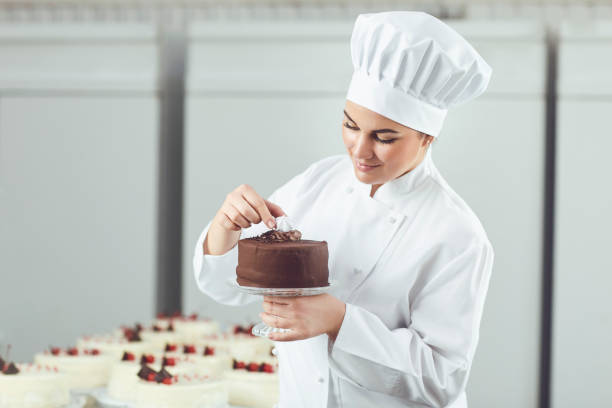 istock Confectioner decorating chocolate cake in pastry shop. 1190426294