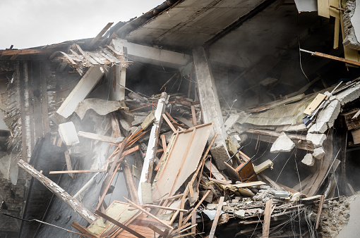 Restos de huracán o terremoto después de desastres daños en casas viejas en ruinas con techo y pared colapsadas con polvo en el aire photo