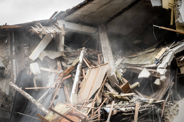Remains of hurricane or earthquake aftermath disaster damage on ruined old houses with collapsed roof and wall with dust in the air stock photo