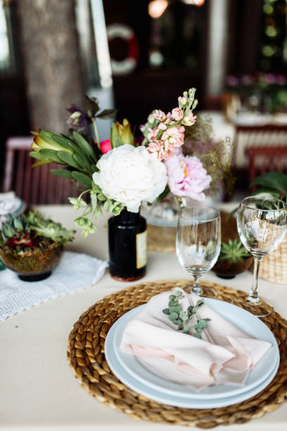 istock Festive table. A plate on a straw stand, a pink fabric napkin and a eucalyptus branch on it 1190430228