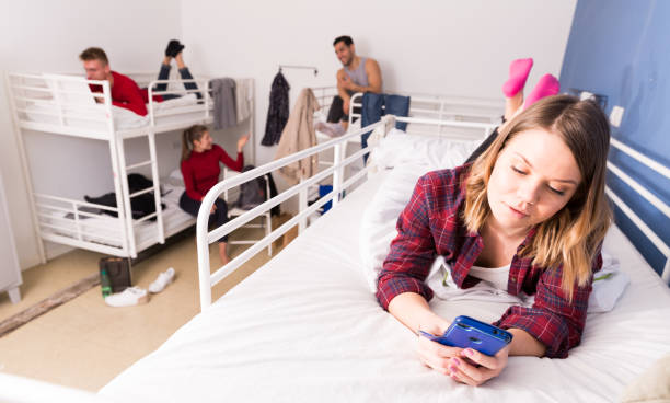istock Woman with phone on bed in hostel 1190430819