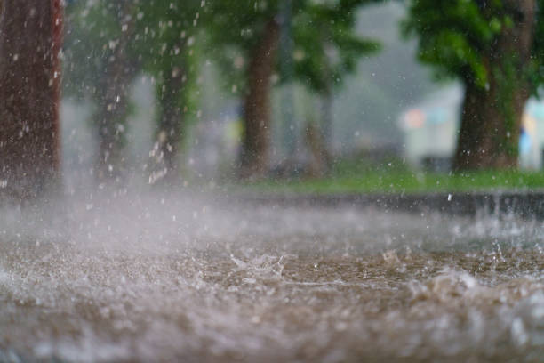 Texture of strong, fresh and powerful water drops and sprays. Puddle with ripple on the road. Tropical rains in Russia, Moscow as a result of global warming