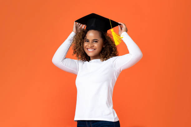 feliz sonriente joven mujer afroamericana con gorra de graduación - poses para fotos de graduación fotografías e imágenes de stock