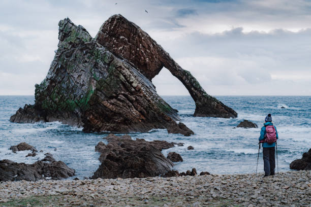 woman at bow fiddle rock, portknockie, schottland - women rear view one person arch stock-fotos und bilder