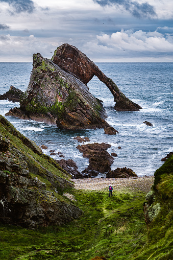 Woman looking out towards Bow Fiddle Rock at Portknockie on the north coast of Morayshire, Scotland.