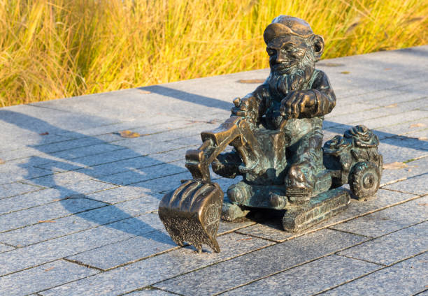 Wroclaw, Poland - November 14 2019: Small sculpture of dwarf operating excavator found near Odra river. One of over 400 sculptures being tourist attraction.