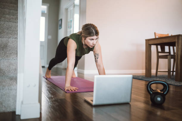 femme observant des tutoriels d'exercice en ligne - living room learning healthy lifestyle one person photos et images de collection