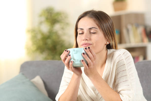 istock Relaxed woman smelling coffee on a couch at home 1190438984