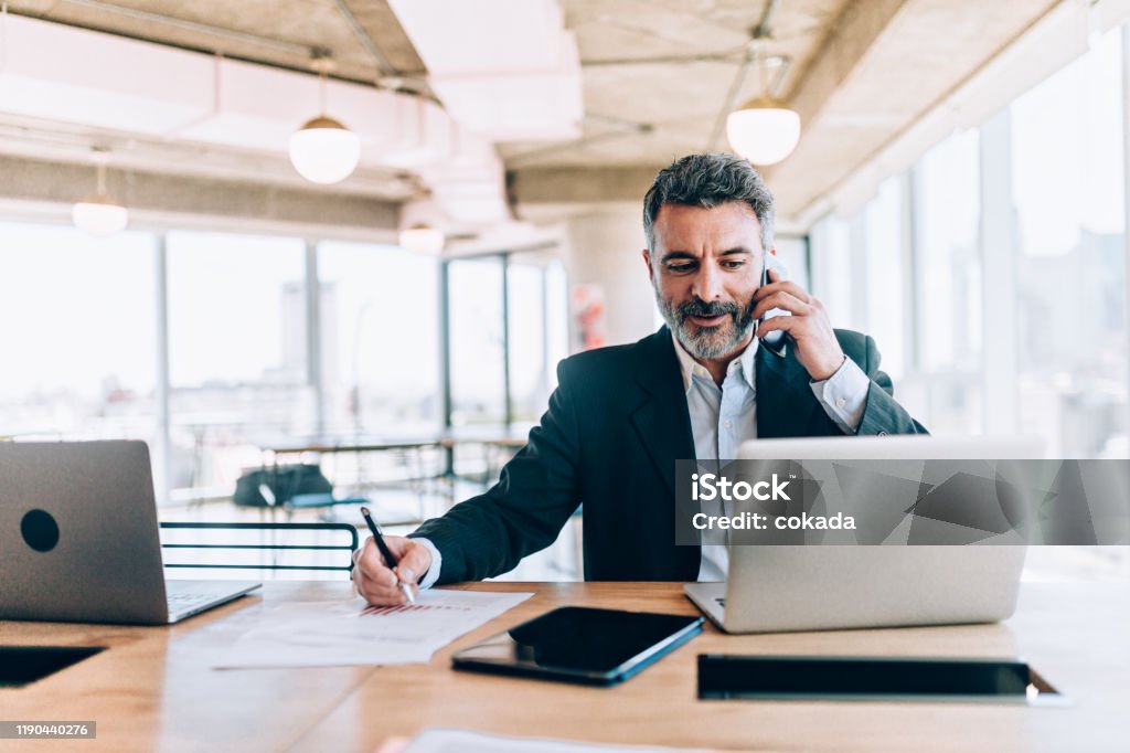 Businessman at the office talking on cell phone Businessman Stock Photo