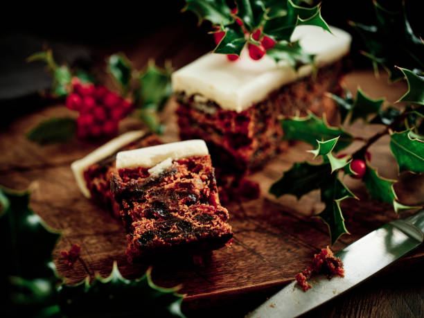 pastel de navidad en una oscura superficie de madera rústica rodeada de holly recién recogido. - tarta de navidad fotografías e imágenes de stock