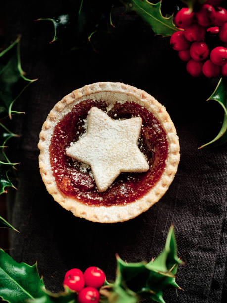 istock Single Mince Pie topped with a star shape surrounded by freshly picked Holly on a black linen surface. 1190442173