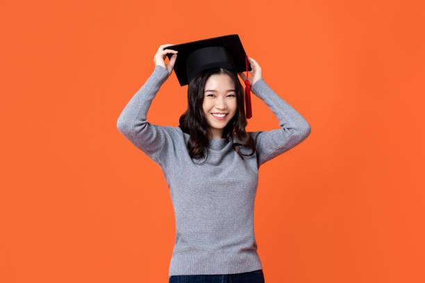 felice sorridente giovane donna asiatica che indossa il berretto da laurea - graduation student women beauty foto e immagini stock