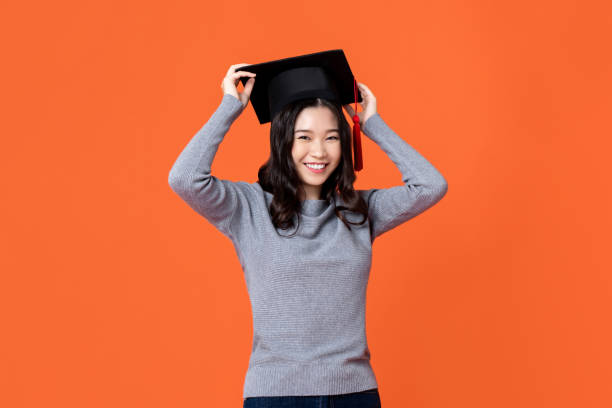 mulher asiática nova de sorriso de sorriso feliz que desgasta o tampão da graduação - graduation student women beauty - fotografias e filmes do acervo