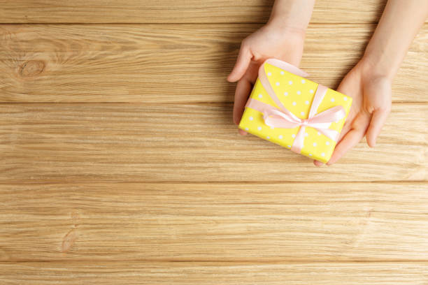 istock gift box in the hands on a wooden background 1190447869
