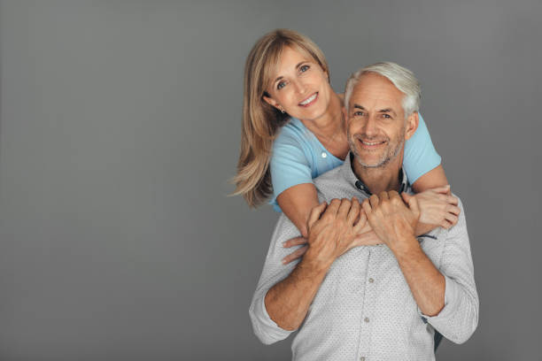 istock Affectionate mature woman hugging her husband against a gray background 1190448125