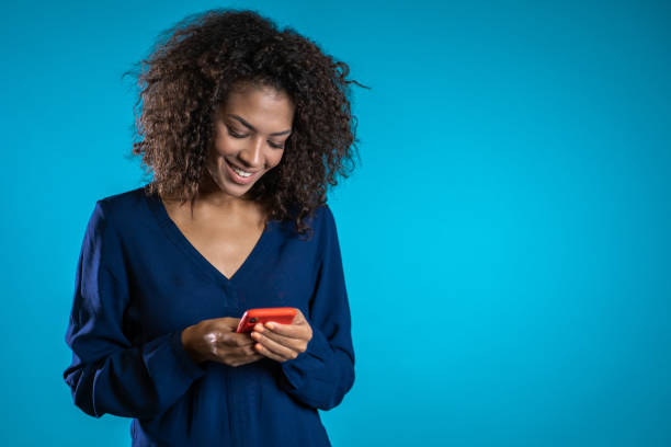 istock Girl with mixed race appearance playing game on smartphone on blue studio wall. Using modern technology - apps, social networks 1190451397