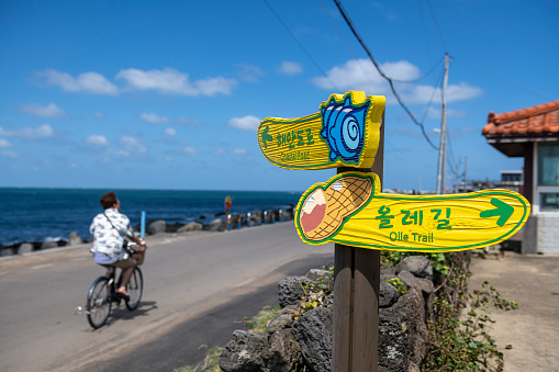 A tourist cycles past a sign giving directions to the coastal road and the Olle Trail on Udo, an island off the coast of Jeju in South Korea.