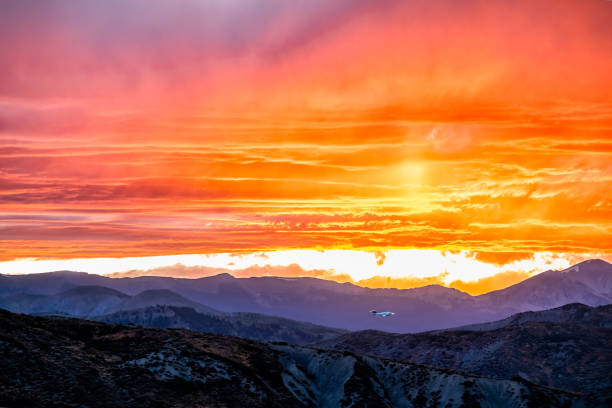 aspen, colorado rocky mountains vibrant vivid colorful sunset orange yellow light in sky with clouds and mountain ridge silhouette - aspen highlands imagens e fotografias de stock