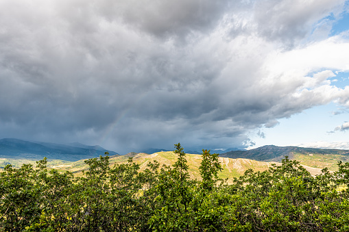 Aspen, Colorado rocky mountains sky wide angle view of blue skyscape and storm clouds foreground of green plants in roaring fork valley