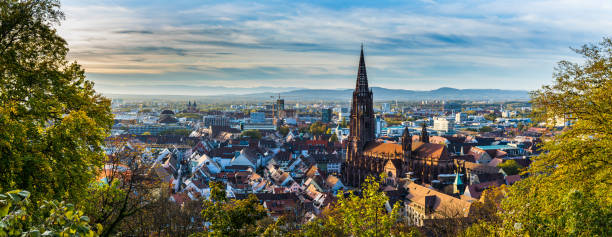 Germany, XXL panorama of city freiburg im breisgau skyline with cathedral muenster in old town in warm sunset light in romantic autumn season, aerial view above cityscape stock photo