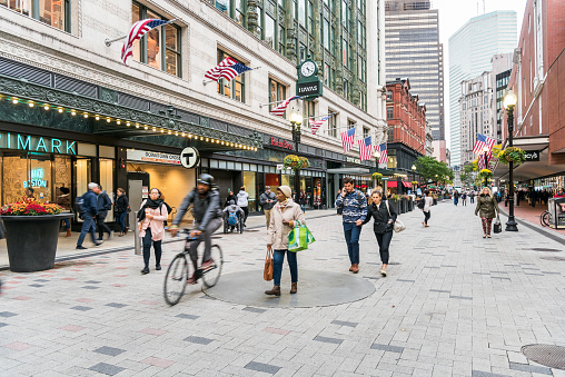 Boston, MA - October 17, 2019: People strolling along Summer Street in Downtown Crossing on a cloudy autumn day. Downtown Crossing, a shopping district within downtown Boston, features large department stores as well as restaurants, souvenir sellers, general retail establishments, and street vendors.