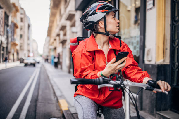 young delivery woman standing on the street - bicycle messenger imagens e fotografias de stock