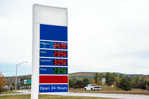 Photo of a petrol station sign with prices along a highway on a cloudy autumn day. Countryside of Vermont, USA.