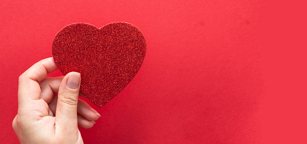 Top view of female hands holding a sparkling glowing heart isolated over flat lay background, copy space for text.