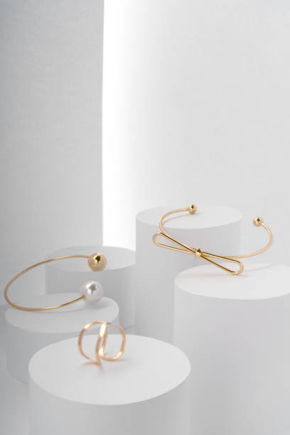 istock Modern golden bracelets and golden ring on white round platforms 1190470945