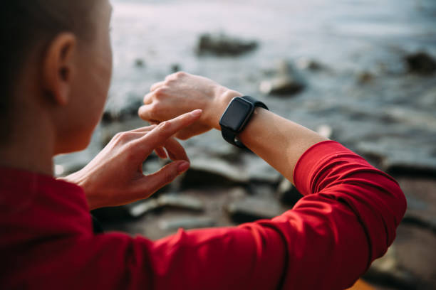 Concept of Biohacking, Modern Technology in Health and Sports. Woman Uses a Smartwatch on Her Hand to Train Healthy Lifestyle, View from behind stock photo