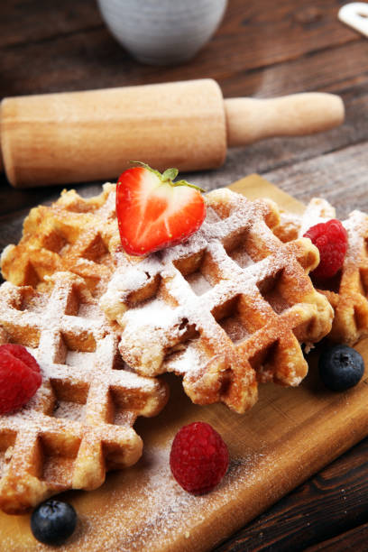 istock Traditional belgian waffles with fresh blueberries, sugar and raspberries on rustic table 1190490995