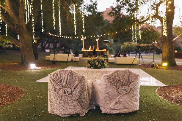 Outdoor wedding reception set up on woods - tables wtih chairs, tall trees and string lights, evening wedding