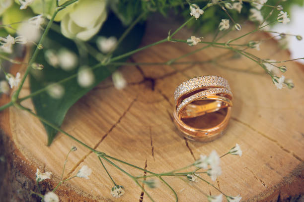 свадебные кольца на деревянном пне с цветочными - обручальное кольцо стоковые фото и изображения