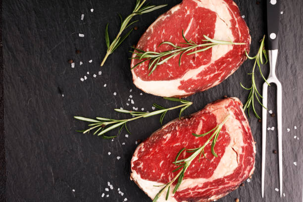 istock Raw fresh meat Ribeye Steak, seasoning and meat fork on rustic background 1190495851