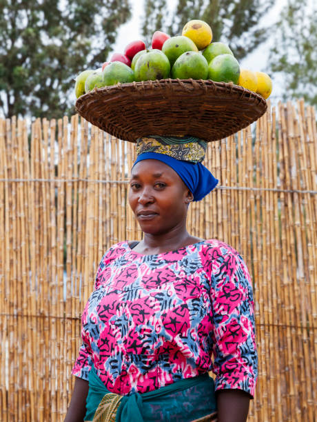 verticale africaine de femme portant un panier avec le fruit sur sa tête, rwanda - porter sur la tête photos et images de collection