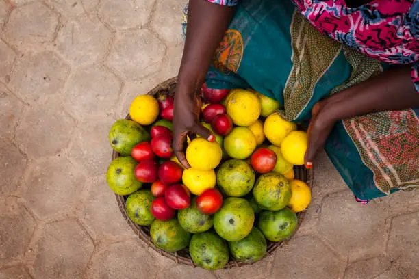 Close up on woman hands and colorful tropical fruit in a basket. Rwanda, Africa