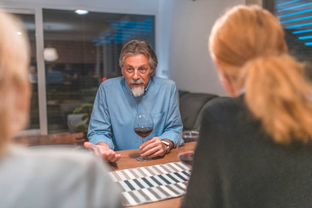 istock Senior man talking with women at dining table 1190505320