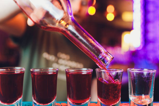 istock Bartender pouring strong alcoholic drink into small glasses on bar, shots. 1190506438