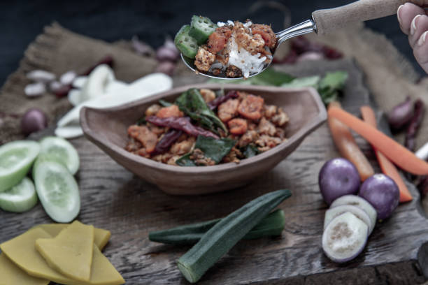 istock The hand is using a spoon to scoop Pork Crackling Chili Paste with fried kaffir lime leaves with the ingredient and fresh vegetables on wood background. 1190506945