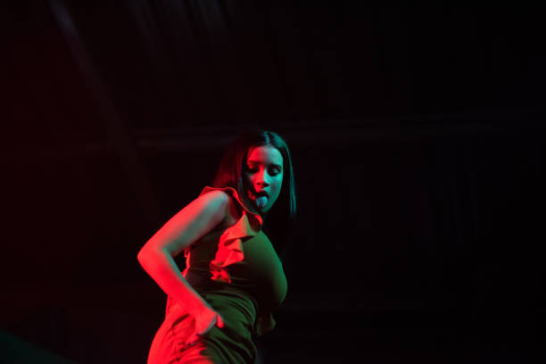 istock Woman dancing on stage with red lights reflecting on her 1190527784