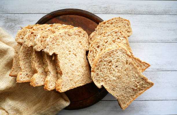 istock Whole grain bread sliced on white wood background. 1190530388