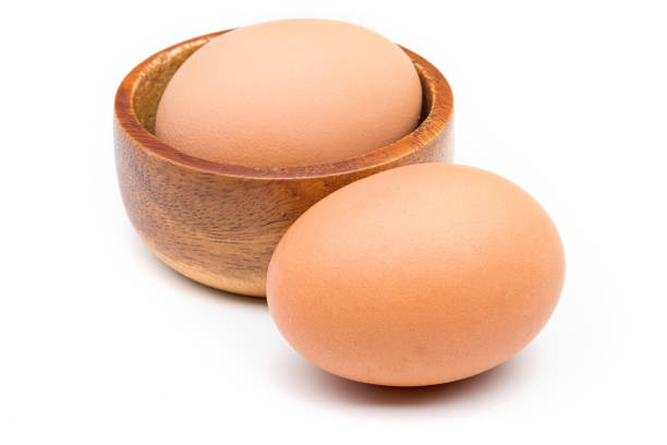 istock Two eggs in a wooden bowl and placed on a white background with a clipping path. 1190530638