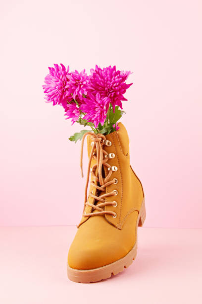 istock Hiking boots with pink flowers inside over the pink pastel background. 1190536559