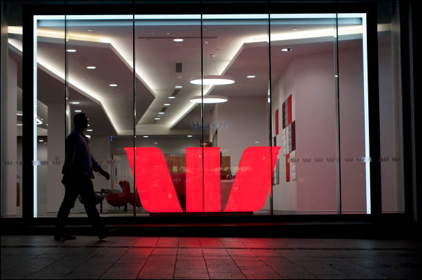 Illuminated Westpac Bank sign Brisbane, Queensland, Australia - 27th November 2019 : View of an illuminated Westpac logo behind a glass wall in the Queenstreet mall in Brisbane, while a man is passing by dealing room photos stock pictures, royalty-free photos & images